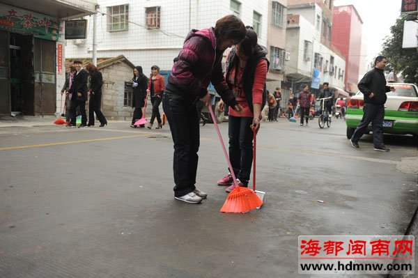 100志愿者冒雨顶班走进社区扫大街